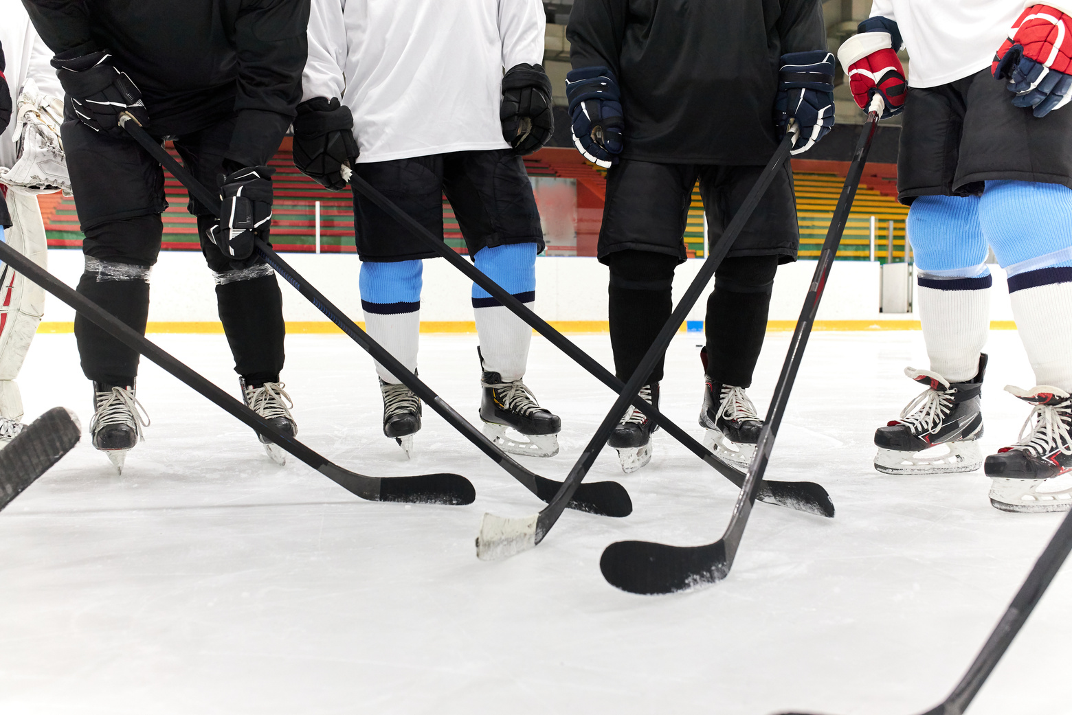 People Standing on Ice Rink while Holding Hockey Sticks